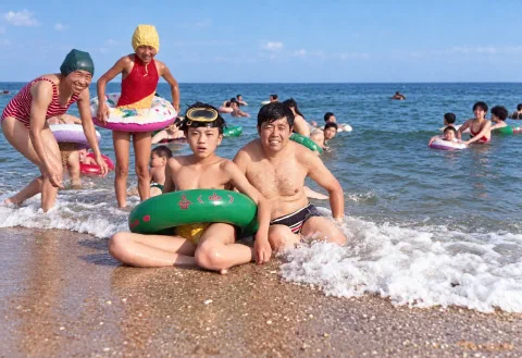 约1993年6月，十五岁的我戴着潜水镜、套着绿色游泳圈，与四十二岁的父亲坐在北戴河海边
